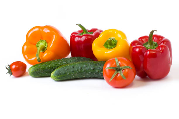 istock Red yellow and orange peppers with tomatoes on a white background. Cucumbers with colorful peppers in composition on a white background. 931477466