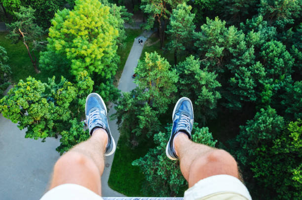 Feet Hanging in the Air First Person View. Above the City Park. The Concept of Flying Over a City Park