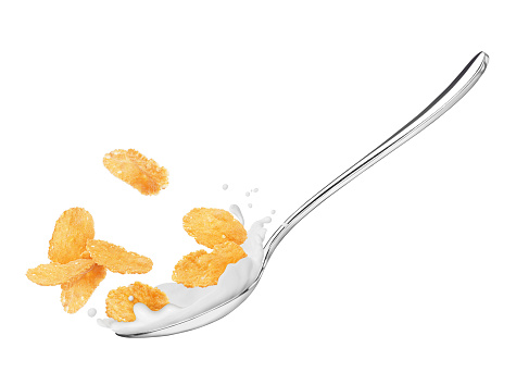 Corn flakes in a spoon with milk close-up, isolated on white background