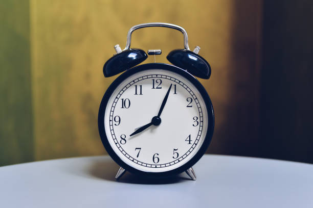 istock Retro alarm clock on table with vintage color background 931483162