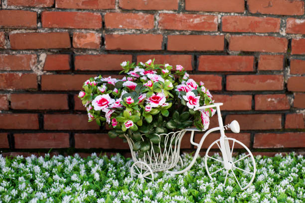 fleurs artificielles sur vélo avec mur de pierre fond - bicycle ornamental garden flower formal garden photos et images de collection