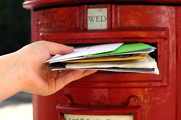 istock hand posting a lot of letters to red british postbox 93149070