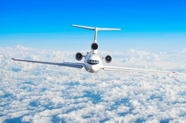 istock Passenger airplane with three engines on the tail flying at flight level high in the sky above the clouds and blue sky. View directly in front, exactly. 931490838
