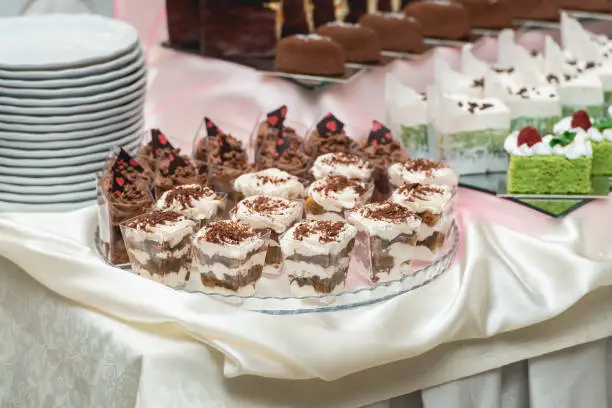 Candybar in a restaurant. Decorated white table fool of sweet pastry. Wedding sweets.