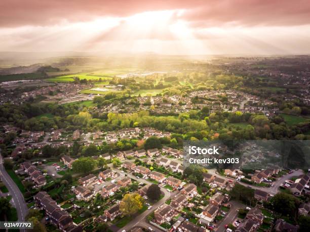 Sun Bursting Through Clouds Over Traditional British Houses With Countryside In The Background Stock Photo - Download Image Now