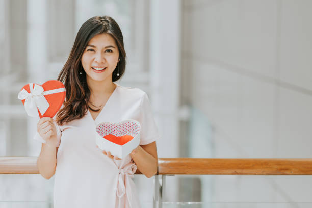 istock Asian woman holding gift box with red heart inside 931505650
