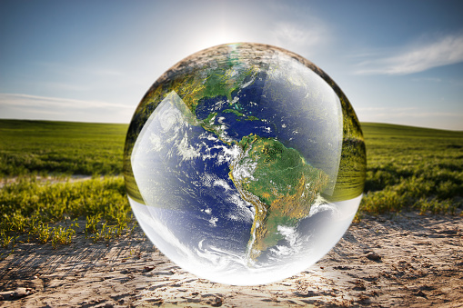 Crystal ball reflecting globe of the earth in nature
