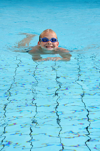 A smiling young swimmer with his head out of the pool water stock photo