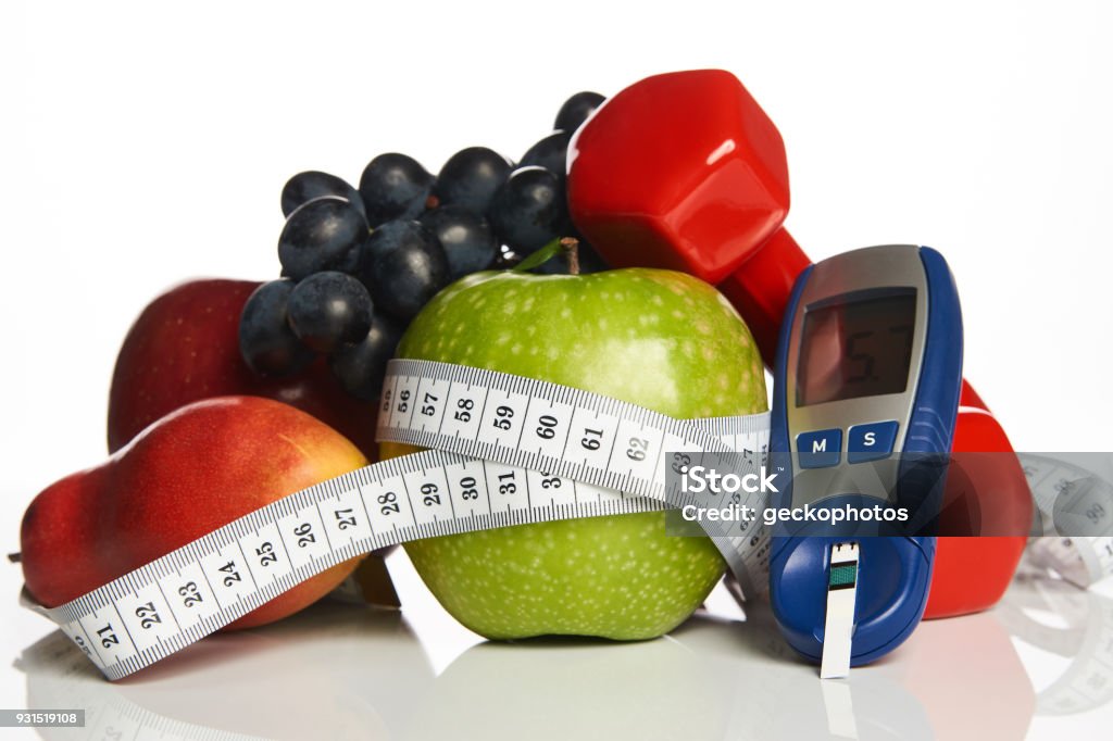 Blood sugar control with healthy organic food and dumbbells with Diabetes monitor, cholesterol diet and healthy food eating nutritional concept with fresh fruits ,nutritionist's, table ,blood ,sugar, control, record ,diabetic ,measuring tool kit Diabetes Stock Photo