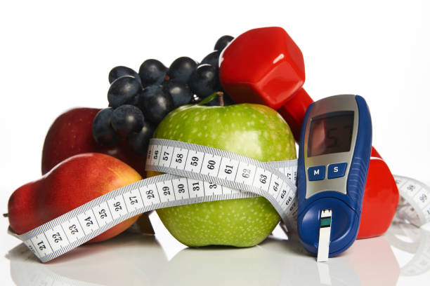 Blood sugar control with healthy organic food and dumbbells with Diabetes monitor, cholesterol diet and healthy food eating nutritional concept with fresh fruits ,nutritionist's, table ,blood ,sugar, control, record ,diabetic ,measuring tool kit diabetes control stock pictures, royalty-free photos & images
