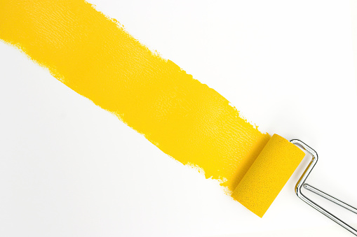 Paintbrush and roller, with yellow paint.