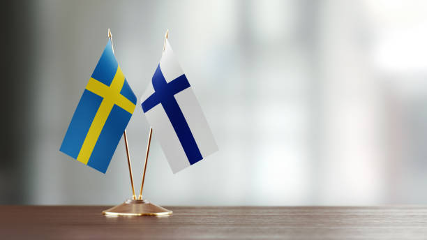 Swedish And Finnish Flag Pair On A Desk Over Defocused Background Swedish and Finnish flag pair on desk over defocused background. Horizontal composition with copy space and selective focus. sweden flag stock pictures, royalty-free photos & images
