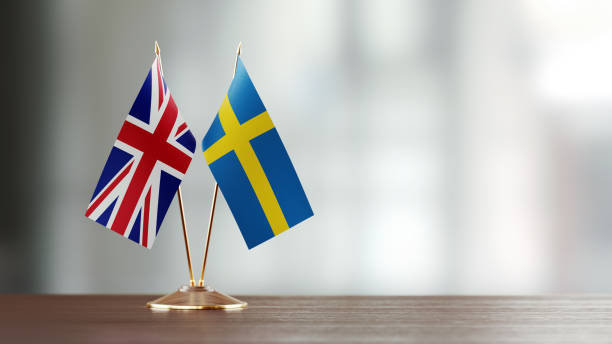 istock Swedish And British Flag Pair On A Desk Over Defocused Background 931528192