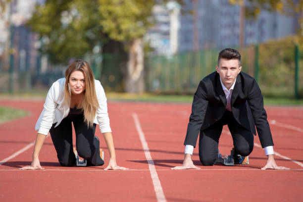 close up of 20 year old businessmen and businesswoman ready to run at start point. - track and field running track sports track beginnings imagens e fotografias de stock