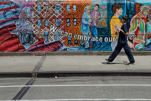 New York, USA - Aug 16, 2017: An unidentified woman walking in  front a graffiti wall. Manhattan.