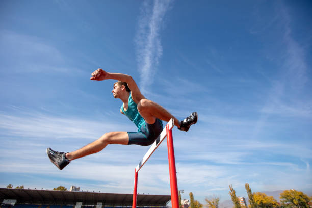 istock Low angle view of determined male athlete jumping over a hurdles 931534406