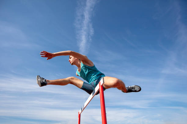 istock Low angle view of determined male athlete jumping over a hurdles 931534430