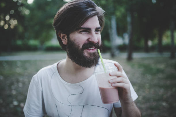 istock Handsome man drinking smoothie in the park 931534556
