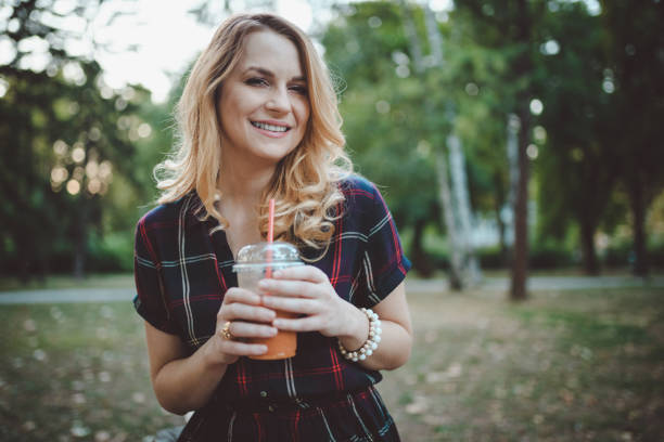 istock Beautiful woman drinking smoothie in the park 931534708