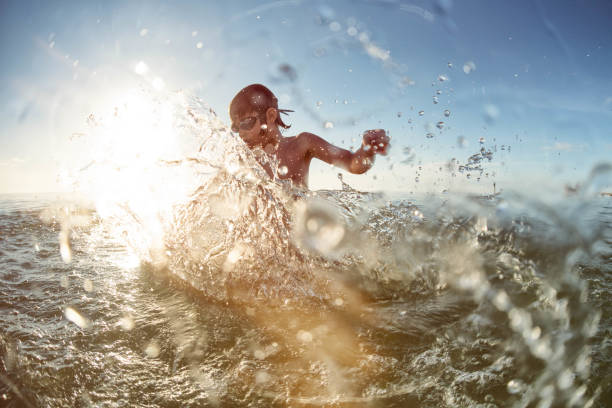 istock Young child splashes in the ocean during sunset 931537988