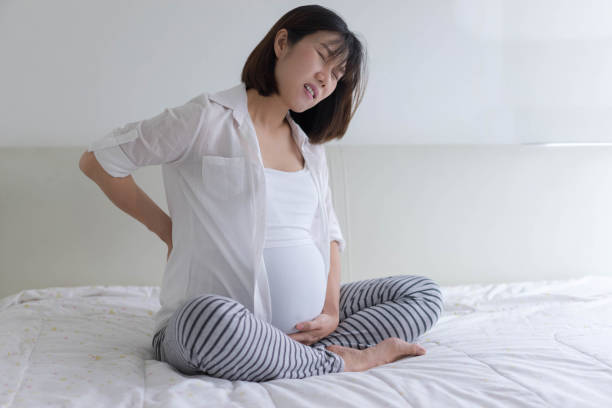 mujer embarazada sufre de dolor de espalda, calambres, malestar - backache pain women illness fotografías e imágenes de stock