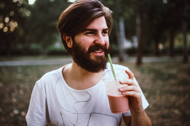 istock Handsome bearded man drinking smoothie in the public park on a lovely sunny day 931546728
