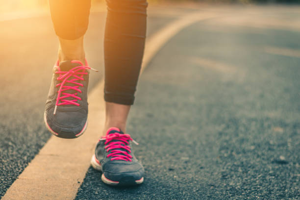 istock Women runner feet on road in workout wellness concept. 931570074