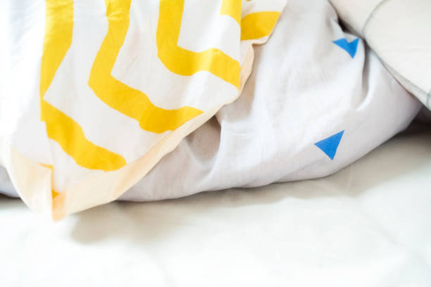 Pillow and blanket on messy bed interior bedroom closeup background