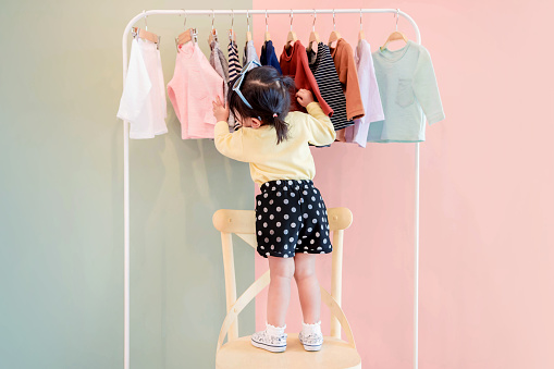 Enfoque suave de dos años edad niño elegir sus propios vestidos de estante del paño de los niños photo
