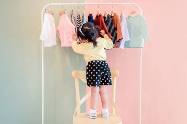 enfoque suave de dos años edad niño elegir sus propios vestidos de estante del paño de los niños - garment fotografías e imágenes de stock