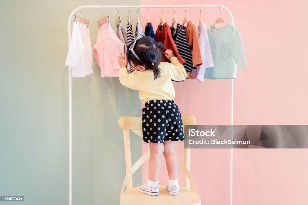Suave foco de um dois anos velho criança escolher seus próprios vestidos de crianças pano Rack - Foto de stock de Criança royalty-free