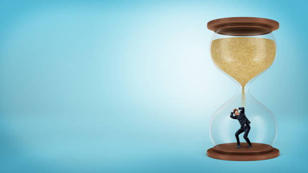 A tiny businessman stands inside a hourglass when the sand only starts to fall over him
