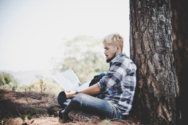 istock Hiker relaxing by tree looking at map, go adventure in mountain. 931578936