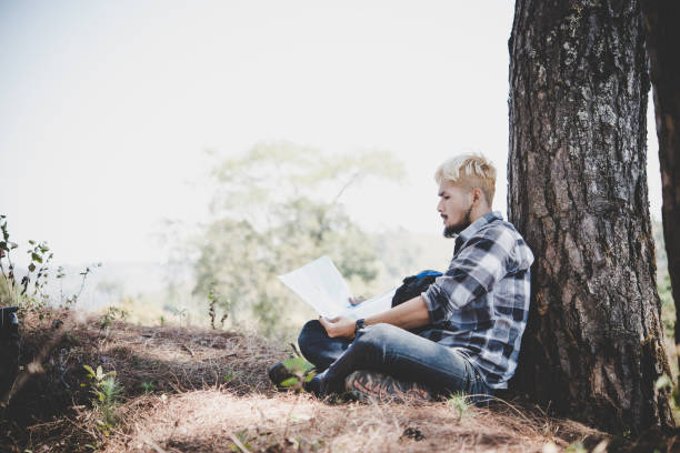 istock Hiker relaxing by tree looking at map, go adventure in mountain. 931578956