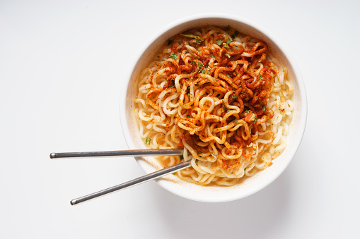 Instant noodle and spicy seasoning in white bowl with chopstick
