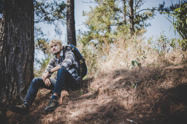 istock Young tired hiker with backpack sitting on the mountain top while resting after active walk. 931582756