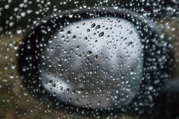 istock Water raindrops on a transparent glass on a black mirror reflector car blurred background 931591138