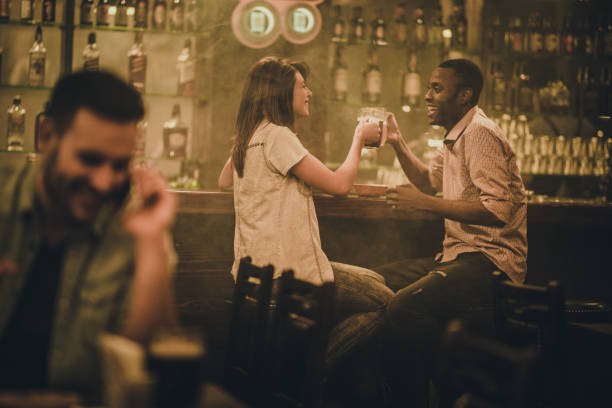 istock Young happy couple having fun while talking and toasting with beer in a bar. 931592432