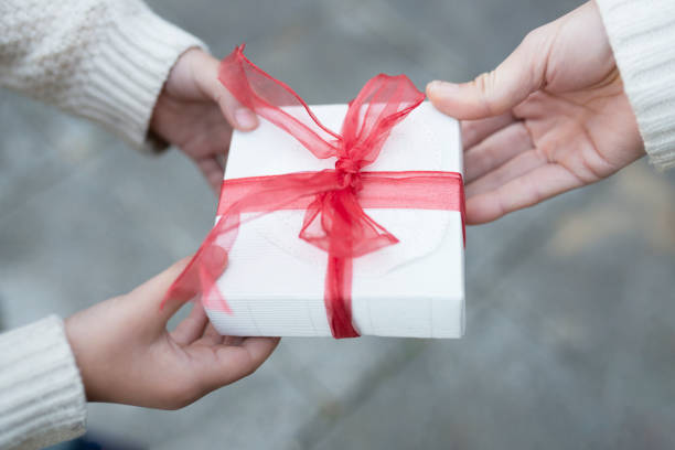 istock Parent and child hand handing present box 931592526