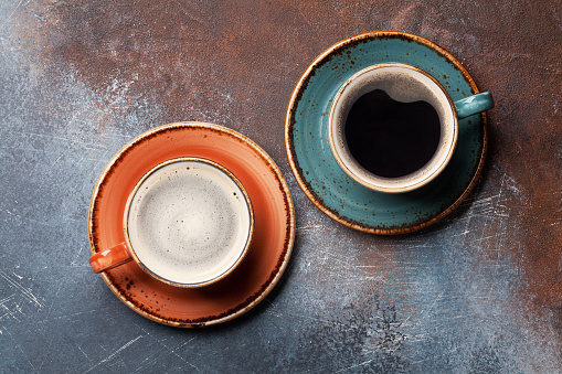 Retro colorful coffee cups on rust background. Top view