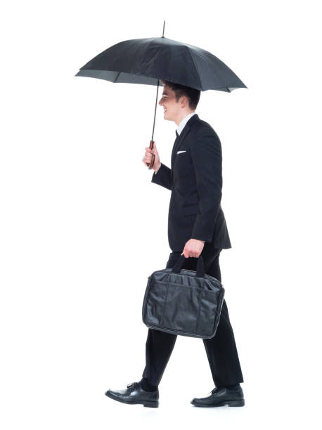 бизнесмен, держащий зонтик, гуляя - 13280 стоковые фото и изображения