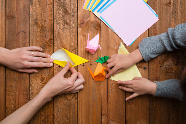 parent et enfant main jouant avec origami - pliage photos et images de collection