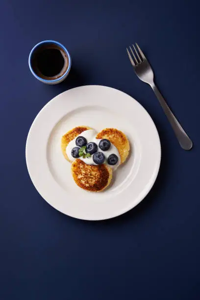cottage cheese pancakes with blueberries and cup of black coffee. top view