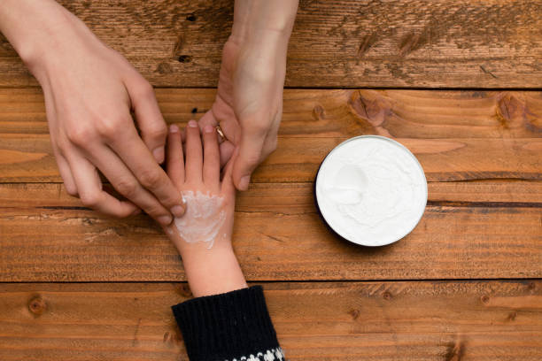 Mother using hand cream in hands of child