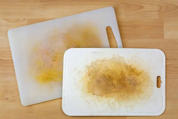 Photo of Dirty white plastic cutting board with dark stains, scratch