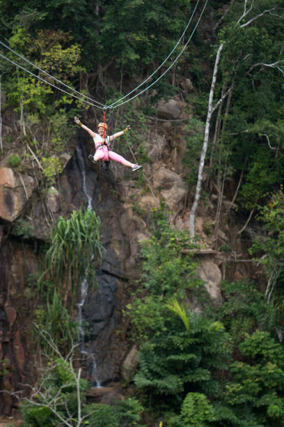 Young happy woman having fun while rappelling from a zip line and looking at camera.