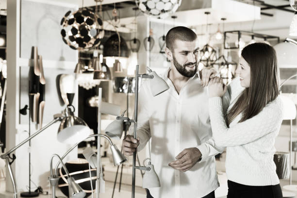 istock Smiling couple customers choosing floor lamp with a long standar 931617324