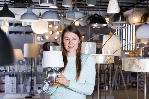 istock Smiling woman customer choosing torchere in store 931617400
