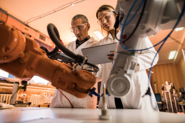 istock Below view of scientists cooperating while working on robotic arm in laboratory. 931633736
