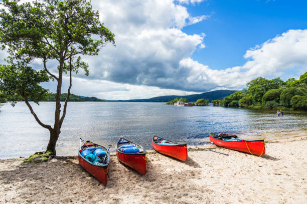 red kayaks on a sandy beach in the summer. loch lomond, scotland, august 2017 - loch rowboat lake landscape imagens e fotografias de stock